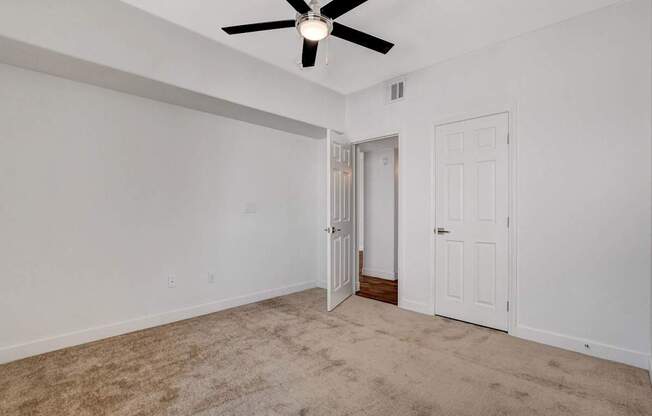 A room with a ceiling fan and carpeted floor.