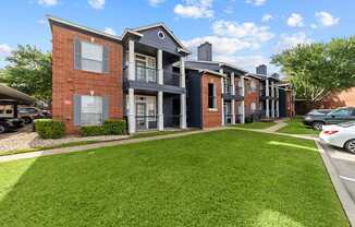 A row of townhouses with a green lawn in front.