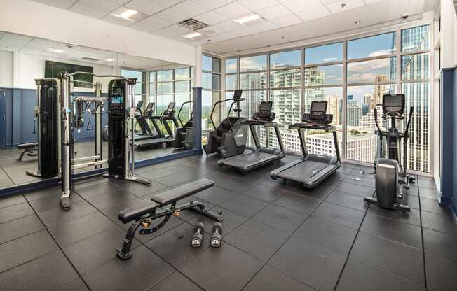 a gym with cardio equipment and a view of the city