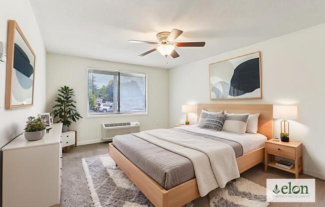 A bedroom with a bed, nightstand, and a plant.