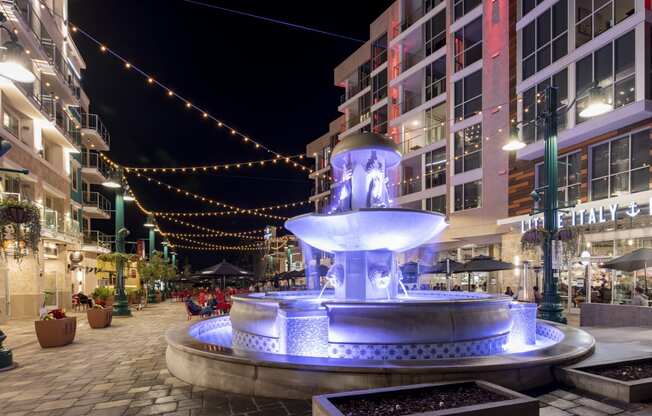 a fountain in the middle of a city street at night
