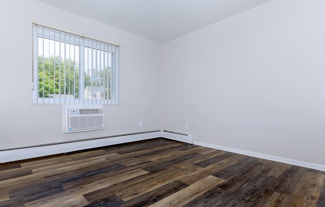 a bedroom with hardwood floors and white walls