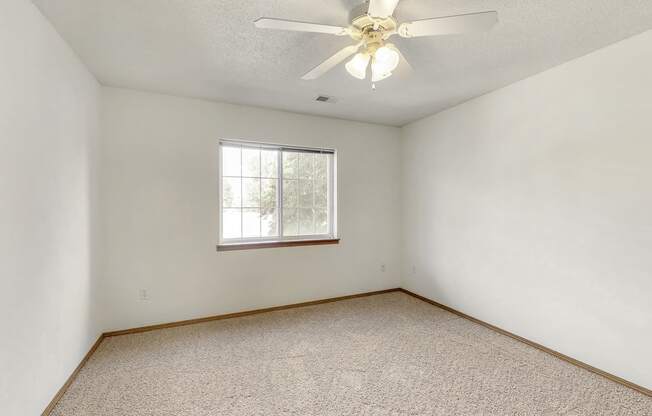 an empty room with a ceiling fan and a window