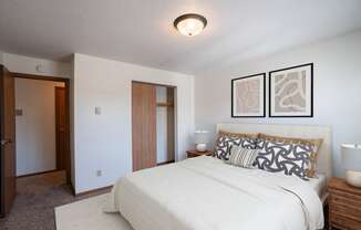 a bedroom with a large bed and a closet. Fargo, ND Southview Village Apartments