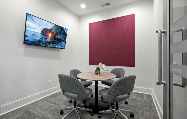 A conference room with a large screen and a table with chairs.