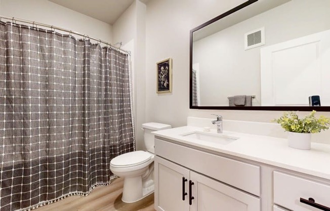 A bathroom with a checkered shower curtain and a white toilet.
