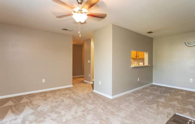 A room with a ceiling fan and carpeted floor.