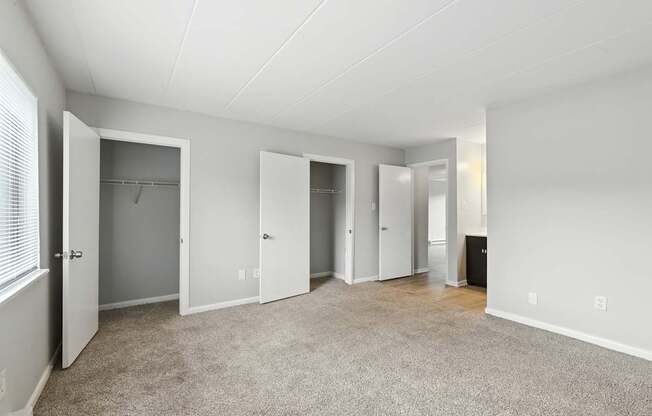 A spacious room with white walls and carpeted floor.
