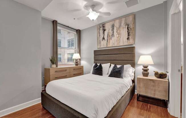 A bedroom with a large bed, two nightstands, and a ceiling fan.