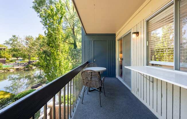 a balcony with a table and chairs and a river