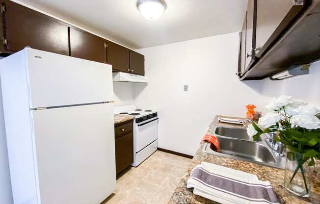 a kitchen with white appliances and a sink and a refrigerator