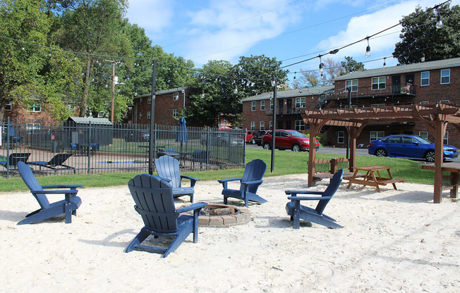 Beach chairs and picnic tables are arranged on a sandy beach.