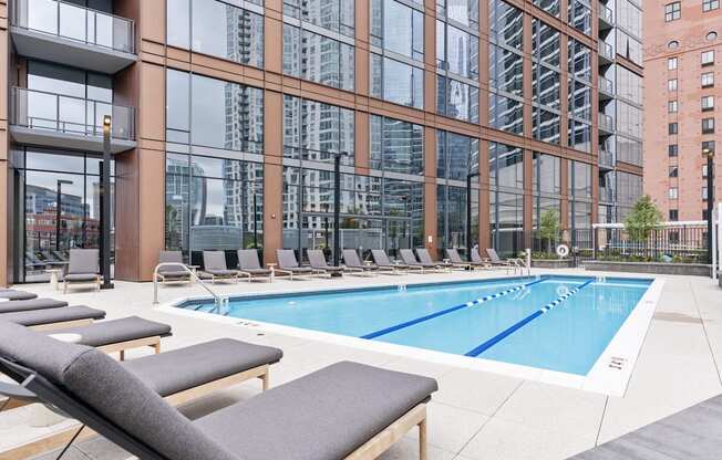 a swimming pool with lounge chairs in front of a tall building at Cassidy on Canal, Chicago, IL, 60606