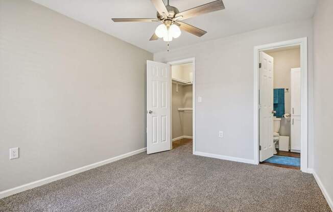 a bedroom with a ceiling fan and a door to a bathroom at The Glen at Highpoint, Dallas, 75243