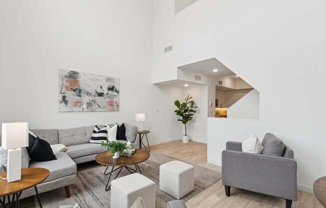 A living room with a grey couch, a coffee table, and a painting on the wall.