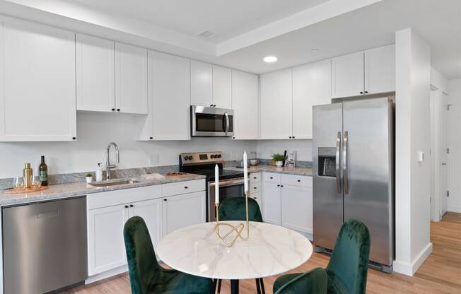 a kitchen with white cabinets and stainless steel appliances and a round table