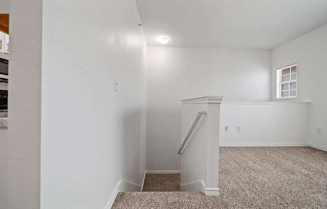 A small room with a carpeted floor and a stairway leading to another room.