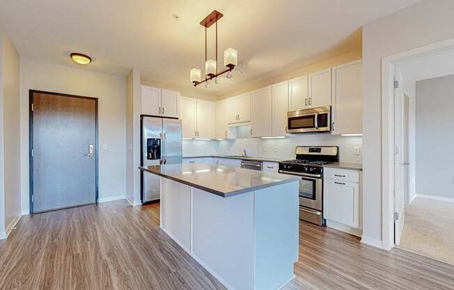 A kitchen with white cabinets and a wooden floor.
