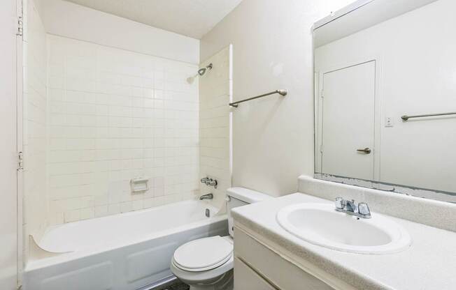 A white bathroom with a toilet, sink, and bathtub.