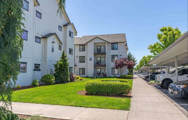 A white apartment building with a green lawn in front at Riverplace Apartment Homes, Independence, OR
