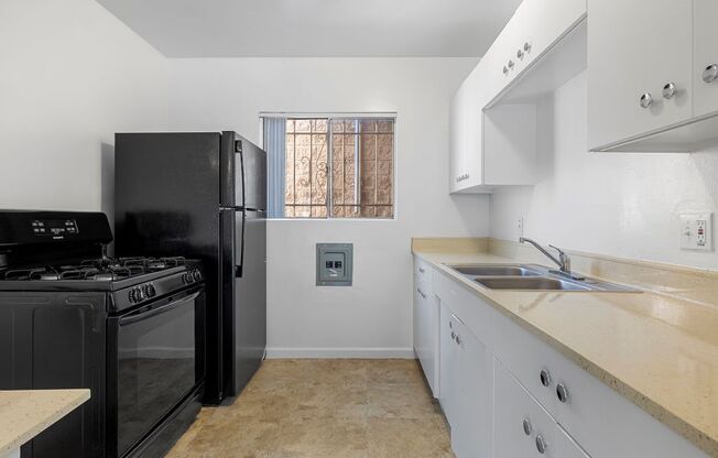 a kitchen with white cabinets and black appliances