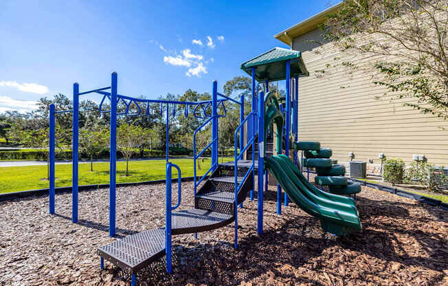 A playground with a blue swing set and a green slide.