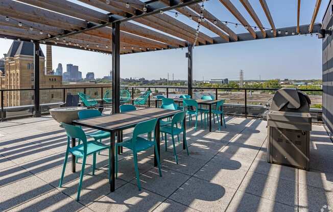 a roof deck with tables and chairs and a city in the background