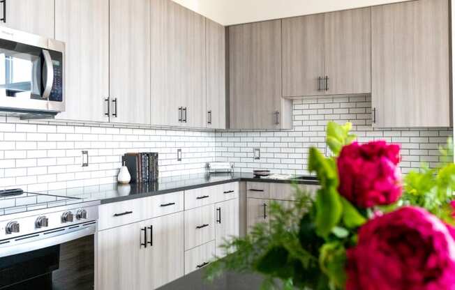 a kitchen with white cabinets and a pink flower on the counter