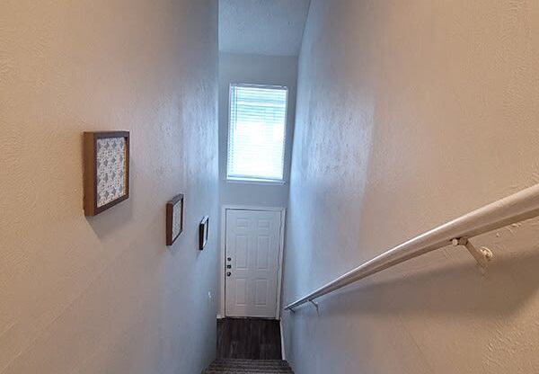 a stairway with a carpeted landing and a window on the top of it at Ivy Plains at Brooks Apartments, San Antonio , 78223