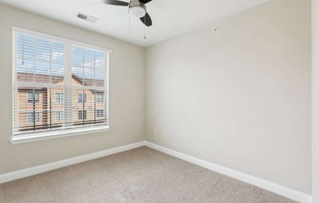 an empty room with a window and a ceiling fan