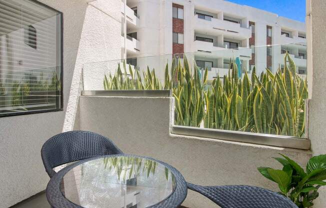 a table and chairs on a balcony with a building in the background  at Masselin Park West, Los Angeles, California