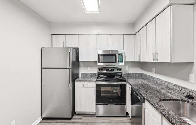 A modern kitchen with a stainless steel refrigerator, oven, and microwave.