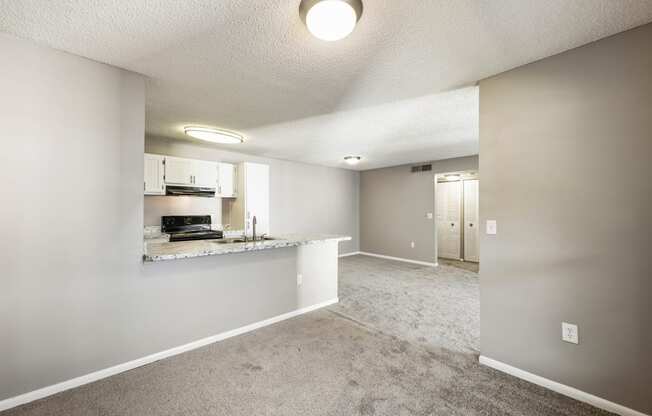 an empty living room and kitchen with a granite counter top