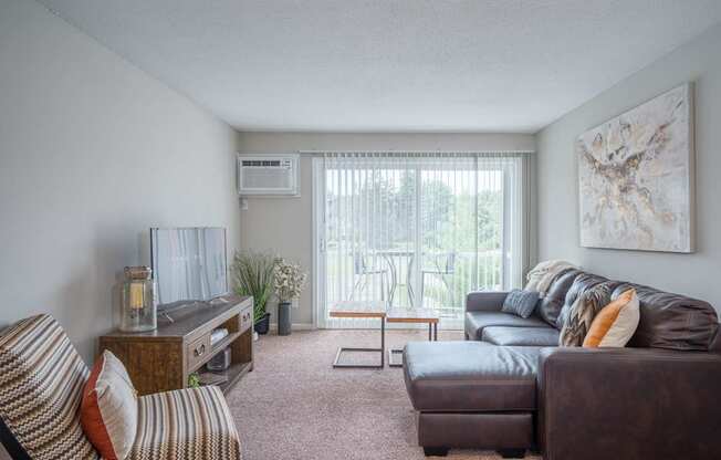 A living room with a brown couch, a striped chair, and a painting on the wall.