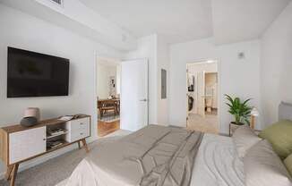 A bedroom with a large bed and a TV on the wall.