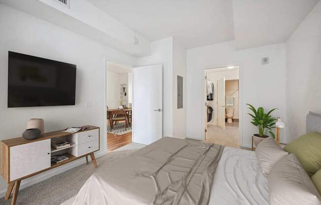A bedroom with a large bed and a TV on the wall.