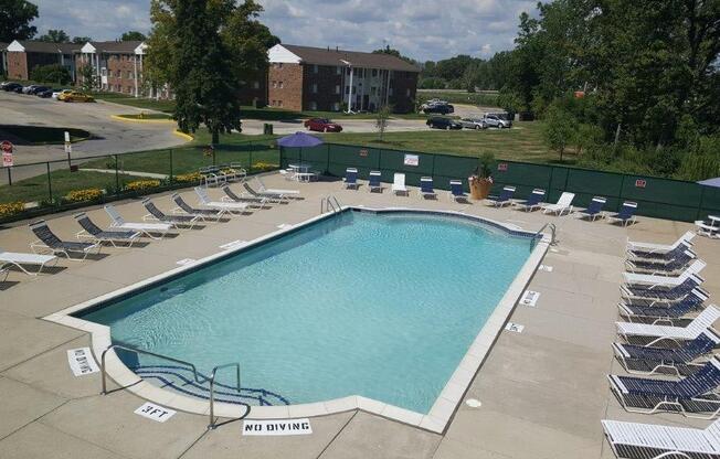 a swimming pool with chaise lounge chairs and a building in the background