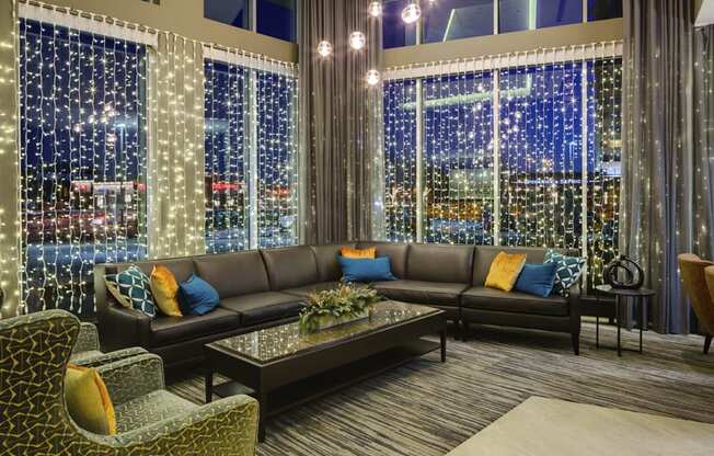 Leather L sofa and two large windows with string lights hanging from them