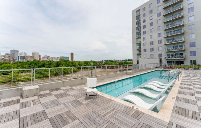 the pool on the rooftop of an apartment building with a city in the background