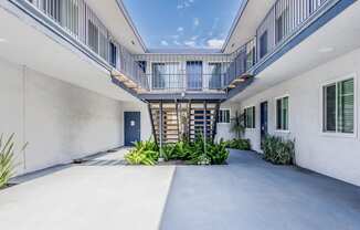 the courtyard of a white building with a blue door