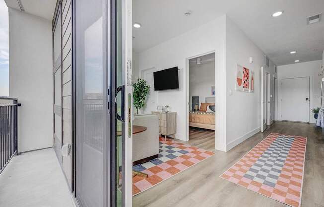A modern living room with a white interior and a glass door leading to a balcony.