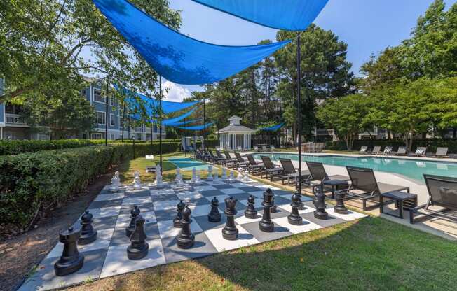 a large chess board is set up next to a swimming pool