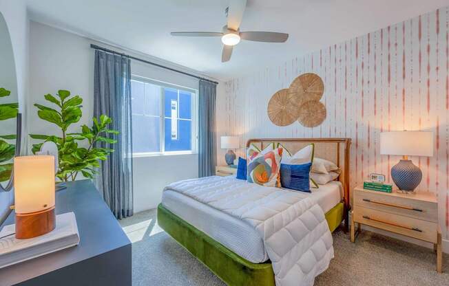 A bedroom with a bed, nightstand, and a plant.