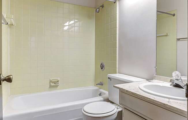 A white toilet sits next to a bathtub in a bathroom.