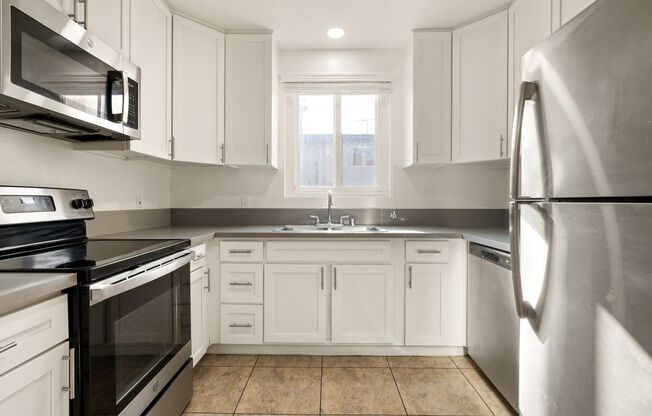 A kitchen with white cabinets and stainless steel appliances.