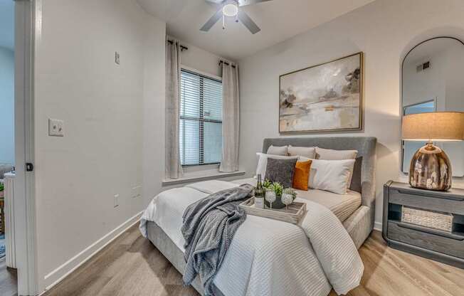 A bedroom with a bed, nightstand, and a painting on the wall.