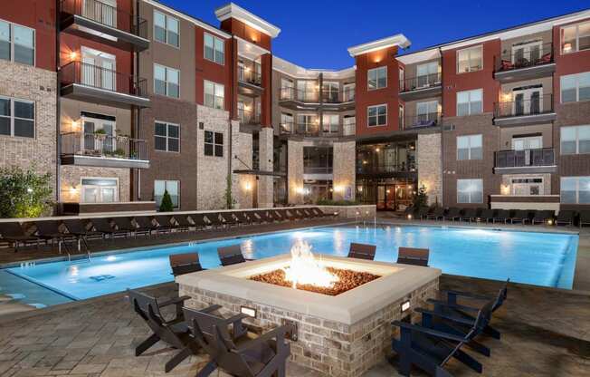 an outdoor pool with a fire pit in front of an apartment building