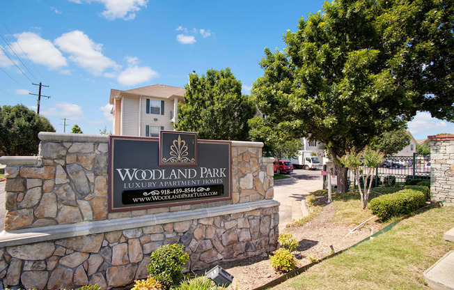 the sign at the entrance of woodlands park apartments