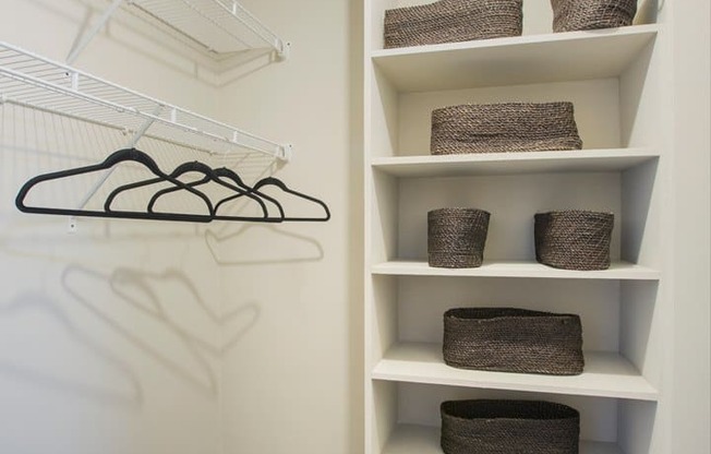 a walk in closet with shelves and baskets