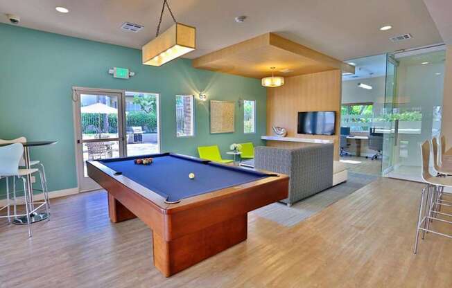 A pool table is in the middle of a room with a television and a couch.